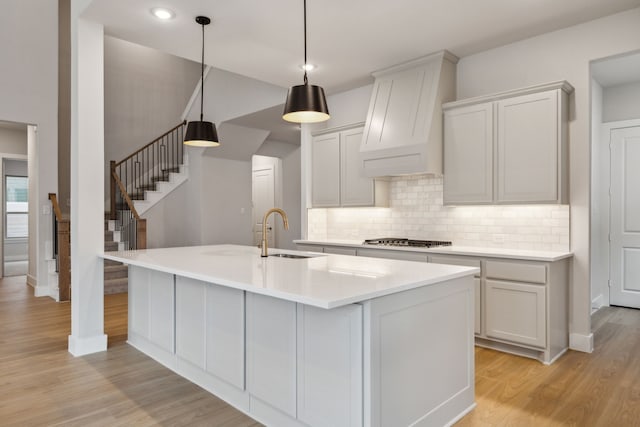 4505 N Summit View Dr, Mckinney, TX 75071 - kitchen with light wood finished floors, backsplash, stainless steel gas stovetop, light countertops, and a kitchen island with sink