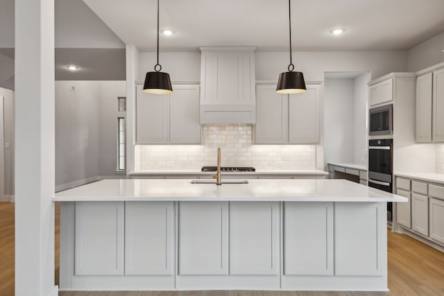 4505 N Summit View Dr, Mckinney, TX 75071 - kitchen with appliances with stainless steel finishes, backsplash, light countertops, light wood-type flooring, and an island with sink