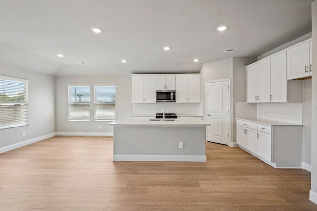 117 Whitlow Dr, Princeton, TX 75071 - kitchen featuring stainless steel microwave, tasteful backsplash, light wood-type flooring, light countertops, and white cabinets
