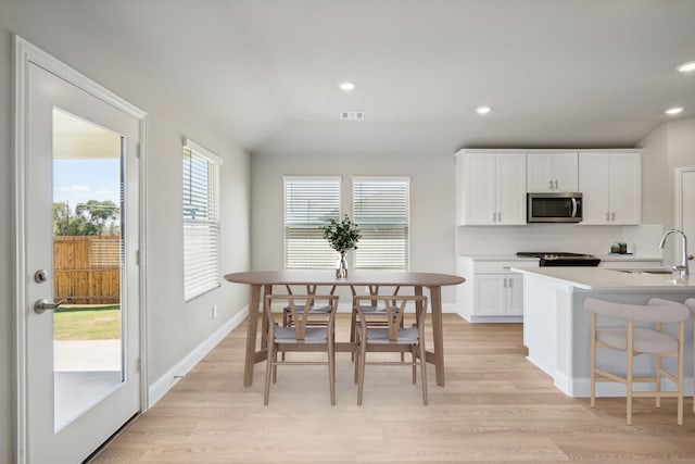 117 Whitlow Dr, Princeton, TX 75071 - kitchen featuring stainless steel microwave, light wood-type flooring, white cabinetry, tasteful backsplash, and light countertops