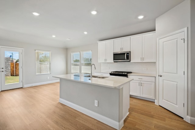 117 Whitlow Dr, Princeton, TX 75071 - kitchen featuring stainless steel microwave, range, tasteful backsplash, light wood finished floors, and white cabinetry