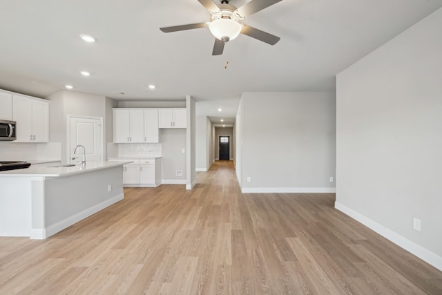 117 Whitlow Dr, Princeton, TX 75071 - kitchen featuring stainless steel microwave, backsplash, recessed lighting, light wood finished floors, and white cabinets