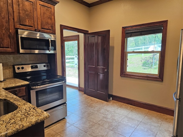 10111 Bluffview Cir, Pilot Point, TX 76258 - kitchen with stainless steel appliances, light stone counters, dark brown cabinetry, and backsplash