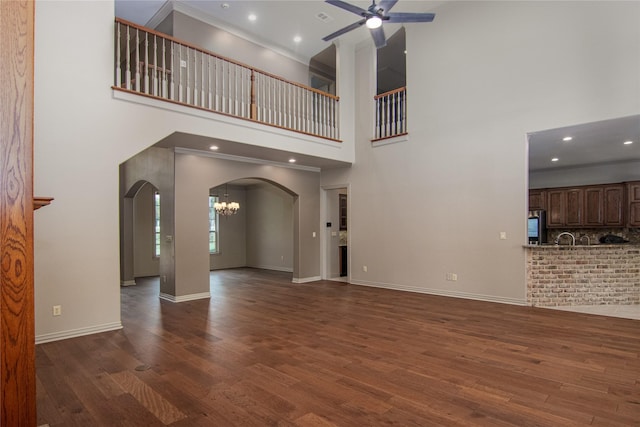 10111 Bluffview Cir, Pilot Point, TX 76258 - unfurnished living room with ceiling fan, arched walkways, a towering ceiling, dark wood-type flooring, and a chandelier