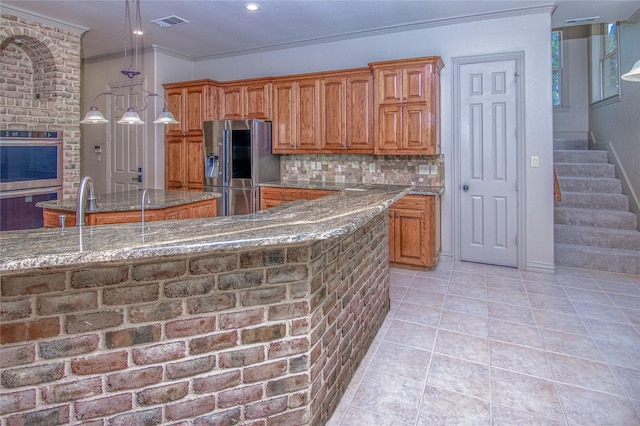 10111 Bluffview Cir, Pilot Point, TX 76258 - kitchen with stainless steel appliances, brown cabinets, stone countertops, crown molding, and light tile patterned floors