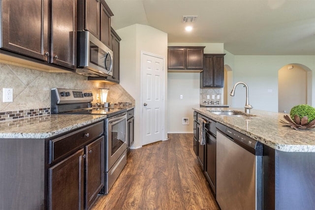 3008 Skinner Dr, Waco, TX 76655 - kitchen featuring stainless steel appliances, arched walkways, dark wood-type flooring, dark brown cabinetry, and tasteful backsplash