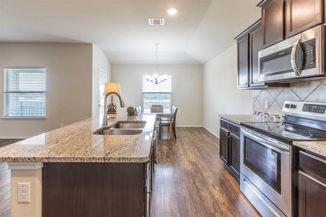 3008 Skinner Dr, Waco, TX 76655 - kitchen with stainless steel appliances, dark wood-style floors, dark brown cabinets, a chandelier, and light stone counters