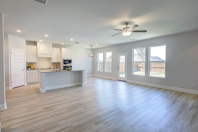 204 Savannah Ln, Oak Point, TX 75068 - kitchen with built in microwave, custom range hood, open floor plan, white cabinets, and light wood-style floors
