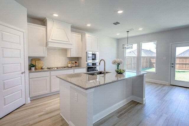 204 Savannah Ln, Oak Point, TX 75068 - kitchen with custom exhaust hood, light wood-style floors, a center island with sink, white cabinetry, and recessed lighting