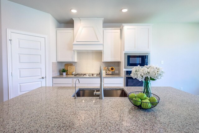 204 Savannah Ln, Oak Point, TX 75068 - kitchen with stainless steel appliances, custom range hood, light stone countertops, white cabinets, and tasteful backsplash