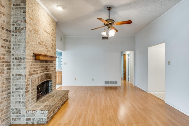 1608 Stroud Ln, Mesquite, TX 75150 - unfurnished living room featuring light wood-type flooring, a textured ceiling, ceiling fan, a brick fireplace, and crown molding