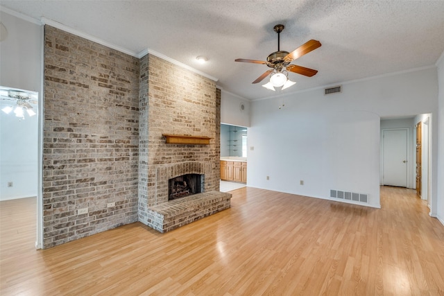 1608 Stroud Ln, Mesquite, TX 75150 - unfurnished living room featuring ceiling fan, light wood-style flooring, a textured ceiling, crown molding, and a fireplace