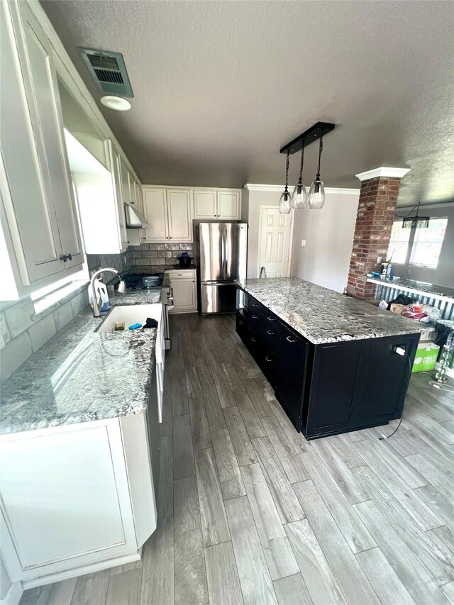 5901 Westgate Dr, Fort Worth, TX 76179 - kitchen with freestanding refrigerator, a textured ceiling, under cabinet range hood, light wood finished floors, and a kitchen island