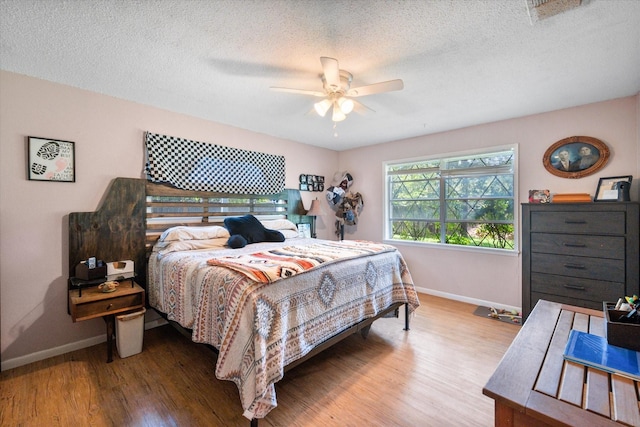 120 Woodland Ave, Corsicana, TX 75110 - bedroom with wood finished floors, a ceiling fan, and a textured ceiling