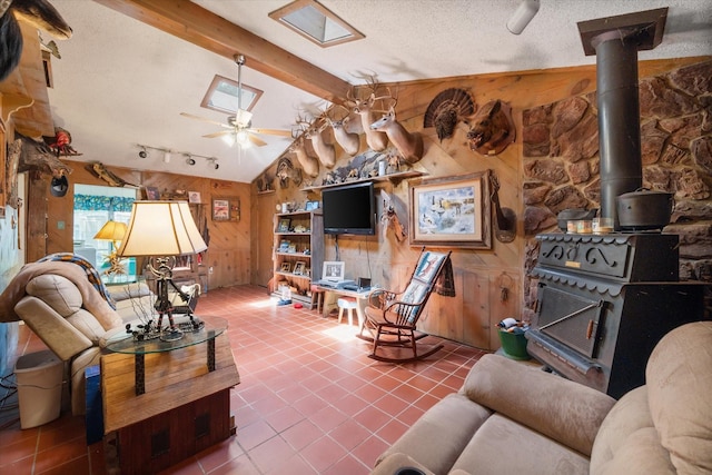 120 Woodland Ave, Corsicana, TX 75110 - living room featuring wooden walls, a wood stove, tile patterned floors, track lighting, and a textured ceiling