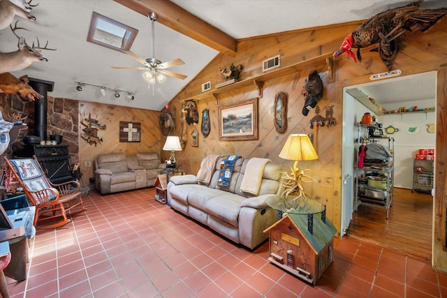 120 Woodland Ave, Corsicana, TX 75110 - tiled living room featuring a wood stove, wood walls, and a ceiling fan