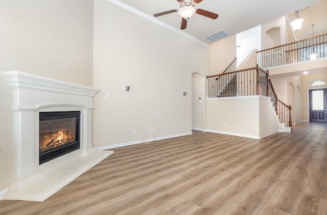 4600 Evenstar Way, Plano, TX 75074 - unfurnished living room with a high ceiling, arched walkways, stairs, a ceiling fan, and a tiled fireplace