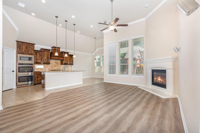 4600 Evenstar Way, Plano, TX 75074 - unfurnished living room featuring a high ceiling, a ceiling fan, light wood-type flooring, a glass covered fireplace, and recessed lighting