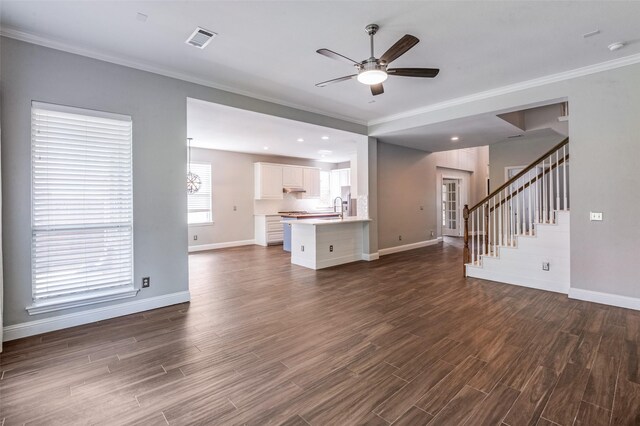 2400 Silverstone Ln, Mckinney, TX 75072 - unfurnished living room featuring a ceiling fan, dark wood-type flooring, crown molding, stairs, and a chandelier