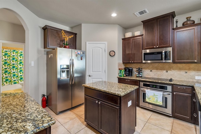 520 Rustic Oak Ln, Mckinney, TX 75072 - kitchen featuring stainless steel appliances, arched walkways, light stone countertops, light tile patterned floors, and backsplash