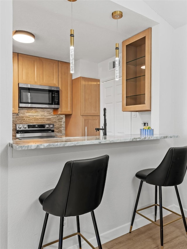 3101 Townbluff Dr Unit 922, Plano, TX 75075 - kitchen with stainless steel appliances, wood finished floors, backsplash, and a breakfast bar area