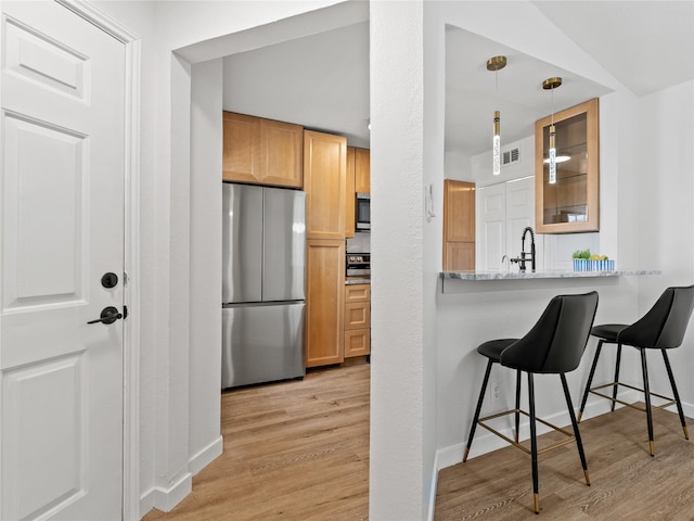 3101 Townbluff Dr Unit 922, Plano, TX 75075 - kitchen featuring appliances with stainless steel finishes, light wood-style floors, a kitchen breakfast bar, and glass insert cabinets