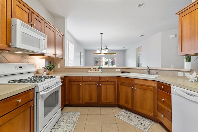 626 Oakland Hills Ln, Frisco, TX 75036 - kitchen with white appliances, brown cabinetry, backsplash, a peninsula, and light countertops