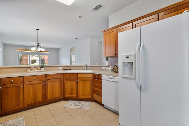626 Oakland Hills Ln, Frisco, TX 75036 - kitchen with white appliances, brown cabinets, a chandelier, light countertops, and light tile patterned floors