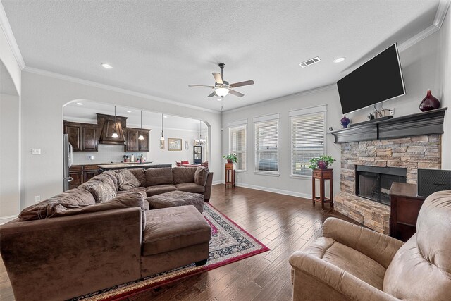 2209 Therese Dr, Waco, TX 76712 - living area featuring arched walkways, ornamental molding, a ceiling fan, dark wood-type flooring, and a fireplace