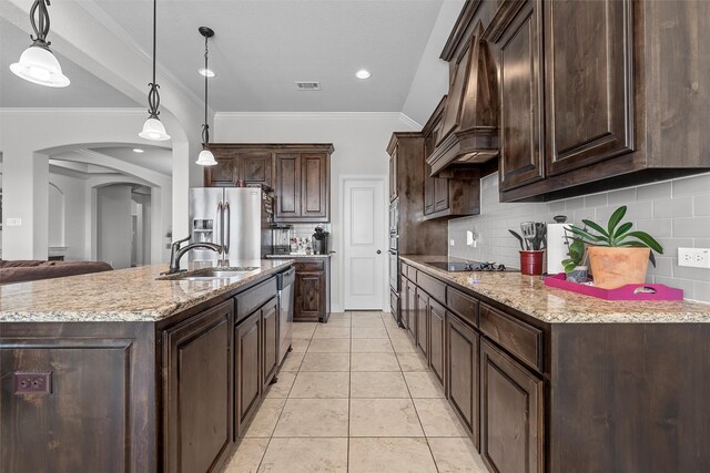 2209 Therese Dr, Waco, TX 76712 - kitchen featuring dark brown cabinets, arched walkways, stainless steel appliances, tasteful backsplash, and pendant lighting