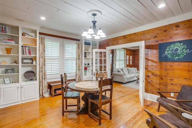 501 W Parks Ave, Waxahachie, TX 75165 - dining space with a chandelier, light wood-style floors, wood walls, crown molding, and built in shelves