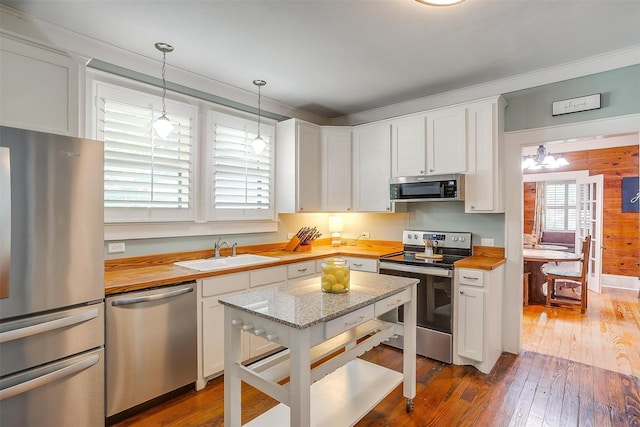 501 W Parks Ave, Waxahachie, TX 75165 - kitchen with appliances with stainless steel finishes, wooden counters, white cabinetry, dark wood finished floors, and ornamental molding