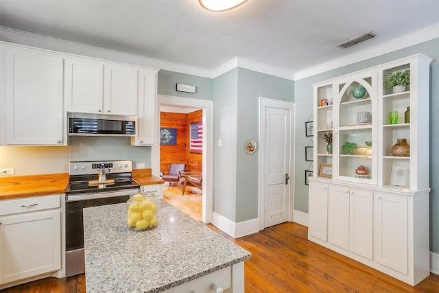 501 W Parks Ave, Waxahachie, TX 75165 - kitchen featuring appliances with stainless steel finishes, white cabinetry, dark wood-style floors, crown molding, and butcher block countertops