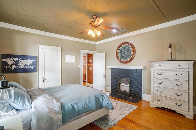 501 W Parks Ave, Waxahachie, TX 75165 - bedroom with light wood-style floors, a fireplace, ornamental molding, and a ceiling fan