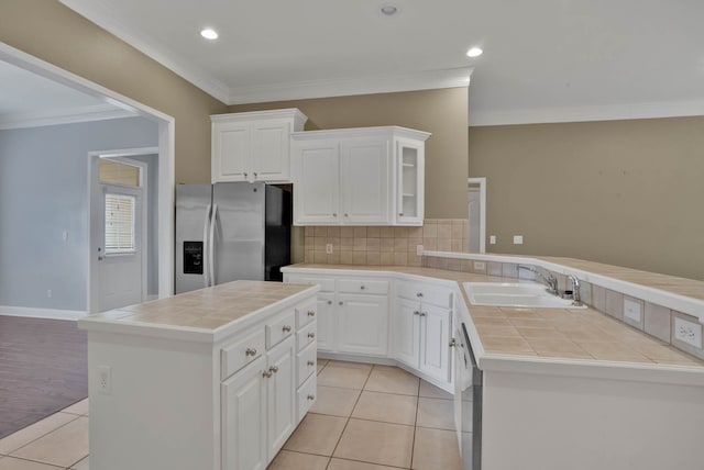 245 Harders Crossing Blvd, Shreveport, LA 71106 - kitchen featuring stainless steel fridge with ice dispenser, tile countertops, light tile patterned floors, crown molding, and tasteful backsplash