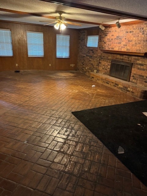 1006 Denmark St, Grand Prairie, TX 75050 - unfurnished living room with brick flooring, a fireplace, wood walls, ceiling fan, and a textured ceiling