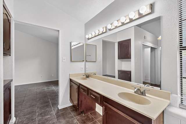 2411 Brookdale Dr, Arlington, TX 76014 - bathroom with double vanity, vaulted ceiling, and tile patterned flooring