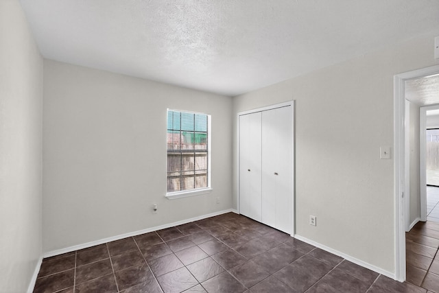 2411 Brookdale Dr, Arlington, TX 76014 - unfurnished bedroom with dark tile patterned floors, a closet, and a textured ceiling