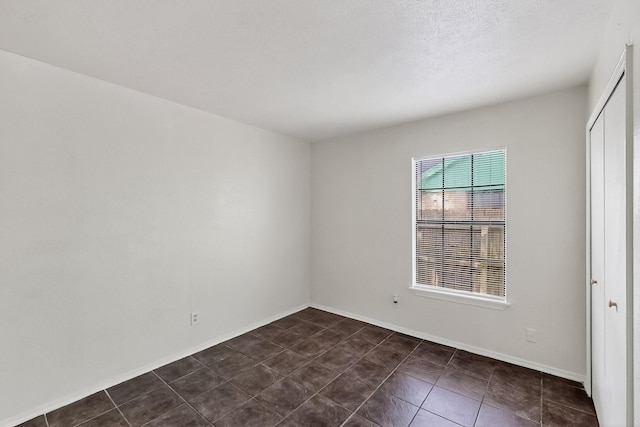 2411 Brookdale Dr, Arlington, TX 76014 - empty room featuring dark tile patterned flooring and baseboards