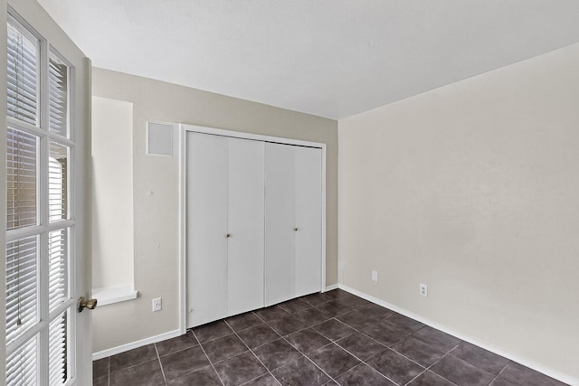 2411 Brookdale Dr, Arlington, TX 76014 - unfurnished bedroom featuring dark tile patterned flooring and a closet
