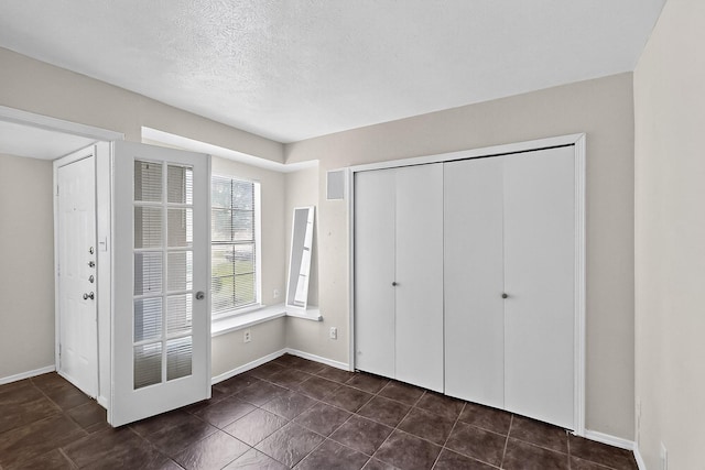 2411 Brookdale Dr, Arlington, TX 76014 - unfurnished bedroom with a closet, dark tile patterned floors, and a textured ceiling