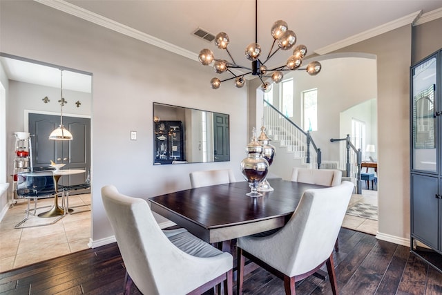 2521 Glen Morris Rd, Carrollton, TX 75007 - dining room featuring dark wood-style floors, a chandelier, arched walkways, crown molding, and stairway