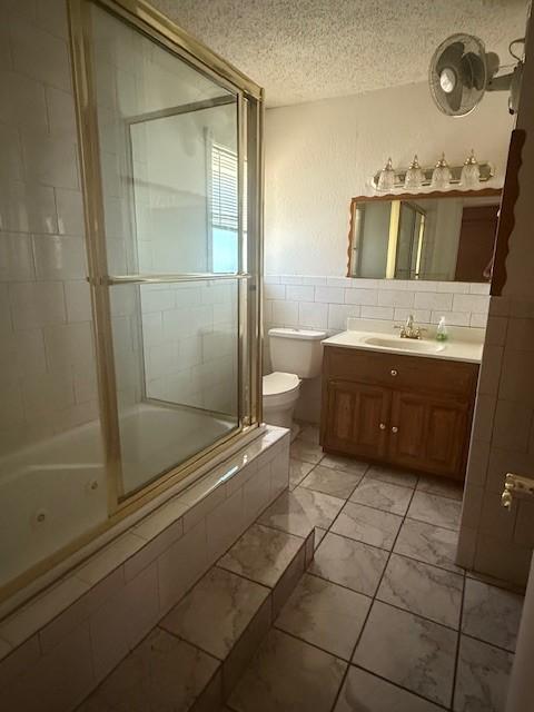 8761 S County Rd, Frisco, TX 75034 - full bath featuring a textured ceiling, a combined bath / shower with jetted tub, vanity, tile walls, and marble finish floors