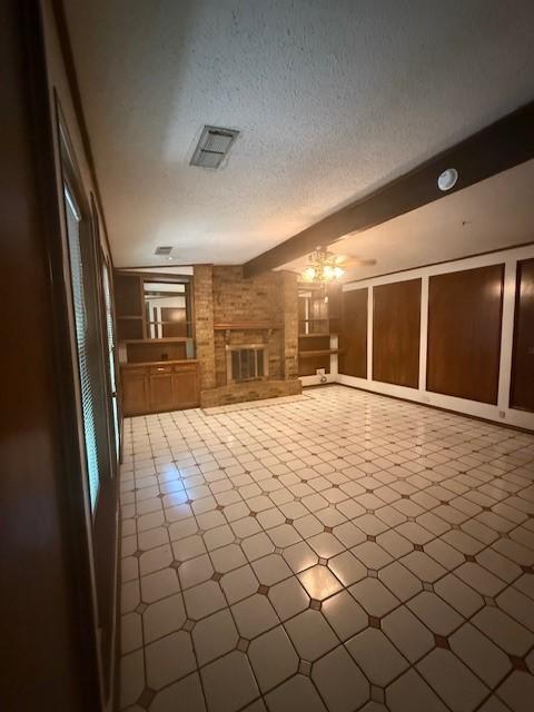 8761 S County Rd, Frisco, TX 75034 - unfurnished living room with a brick fireplace and a textured ceiling