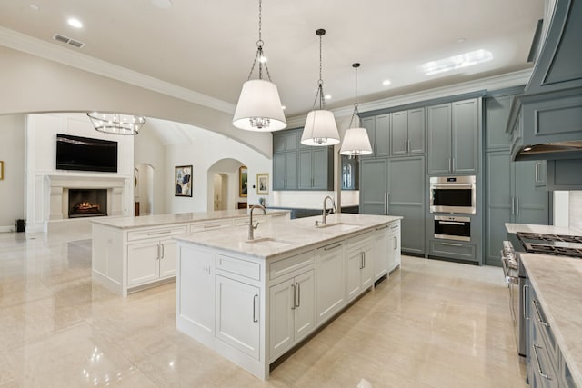 1806 Scenic Cir, Westlake, TX 76262 - kitchen featuring stainless steel gas range oven, a center island with sink, arched walkways, crown molding, and hanging light fixtures