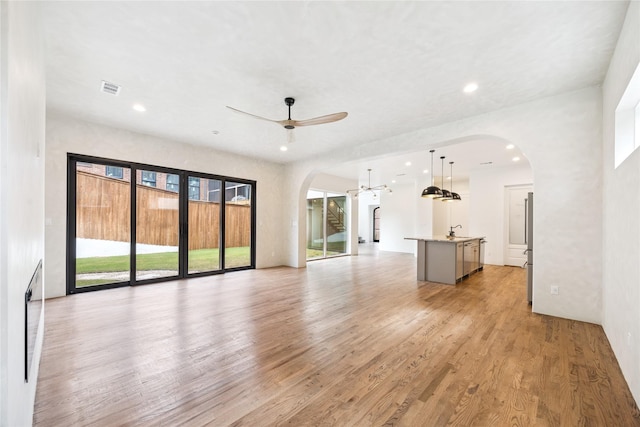 3106 W Jefferson Blvd, Dallas, TX 75211 - unfurnished living room featuring arched walkways, light wood finished floors, ceiling fan, and recessed lighting