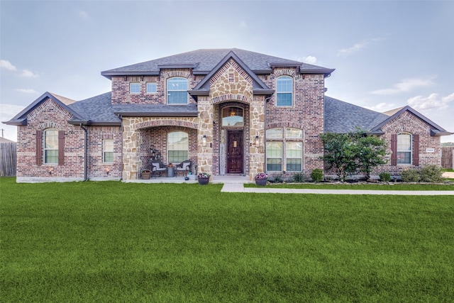 17055 Lochwood Ln, Forney, TX 75126 - french country home featuring a shingled roof, brick siding, and a front lawn