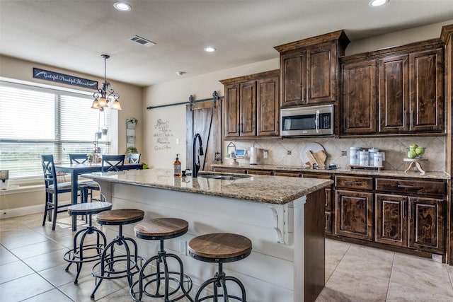 17055 Lochwood Ln, Forney, TX 75126 - kitchen with stainless steel microwave, a barn door, light stone counters, decorative backsplash, and recessed lighting