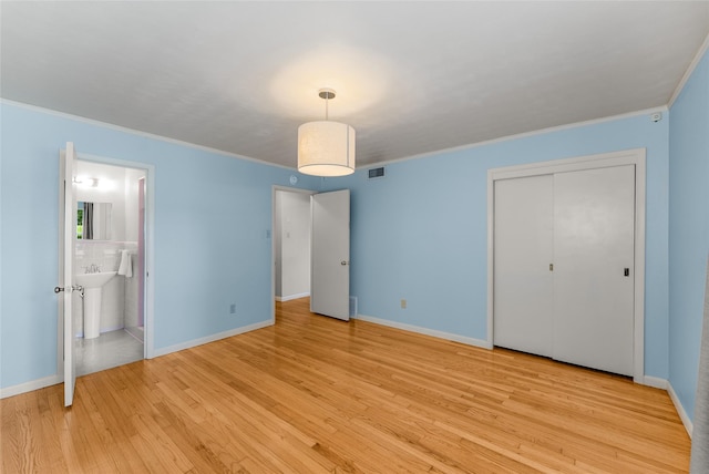 2704 Sunset Ave, Dallas, TX 75211 - unfurnished bedroom featuring light wood finished floors, crown molding, connected bathroom, and a closet