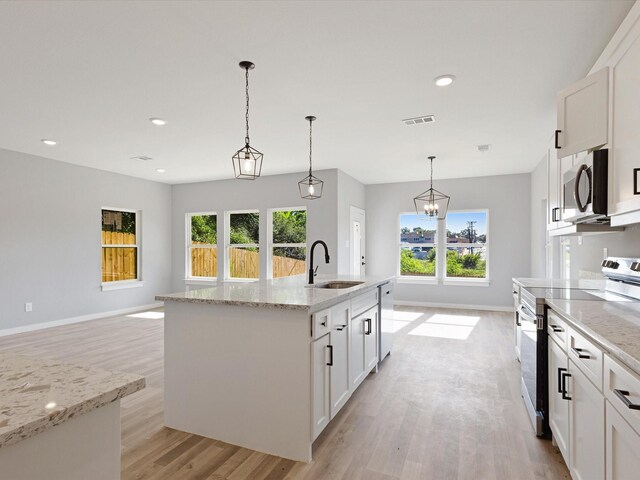 1400 Belzise Ter, Fort Worth, TX 76104 - kitchen with stainless steel appliances, light wood-style flooring, white cabinetry, pendant lighting, and light stone counters
